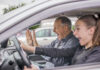 Am I unplugged, unafraid, or unaware? A man and a young woman sitting in a car, both with expressions of surprise and excitement. The man, who appears to be in the passenger seat, has his hands raised while the young woman is holding the steering wheel. They are both reacting to something happening during a driving lesson.