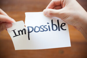 Two hands tearing a piece of paper with the word "Impossible," highlighting the transition to "Possible."