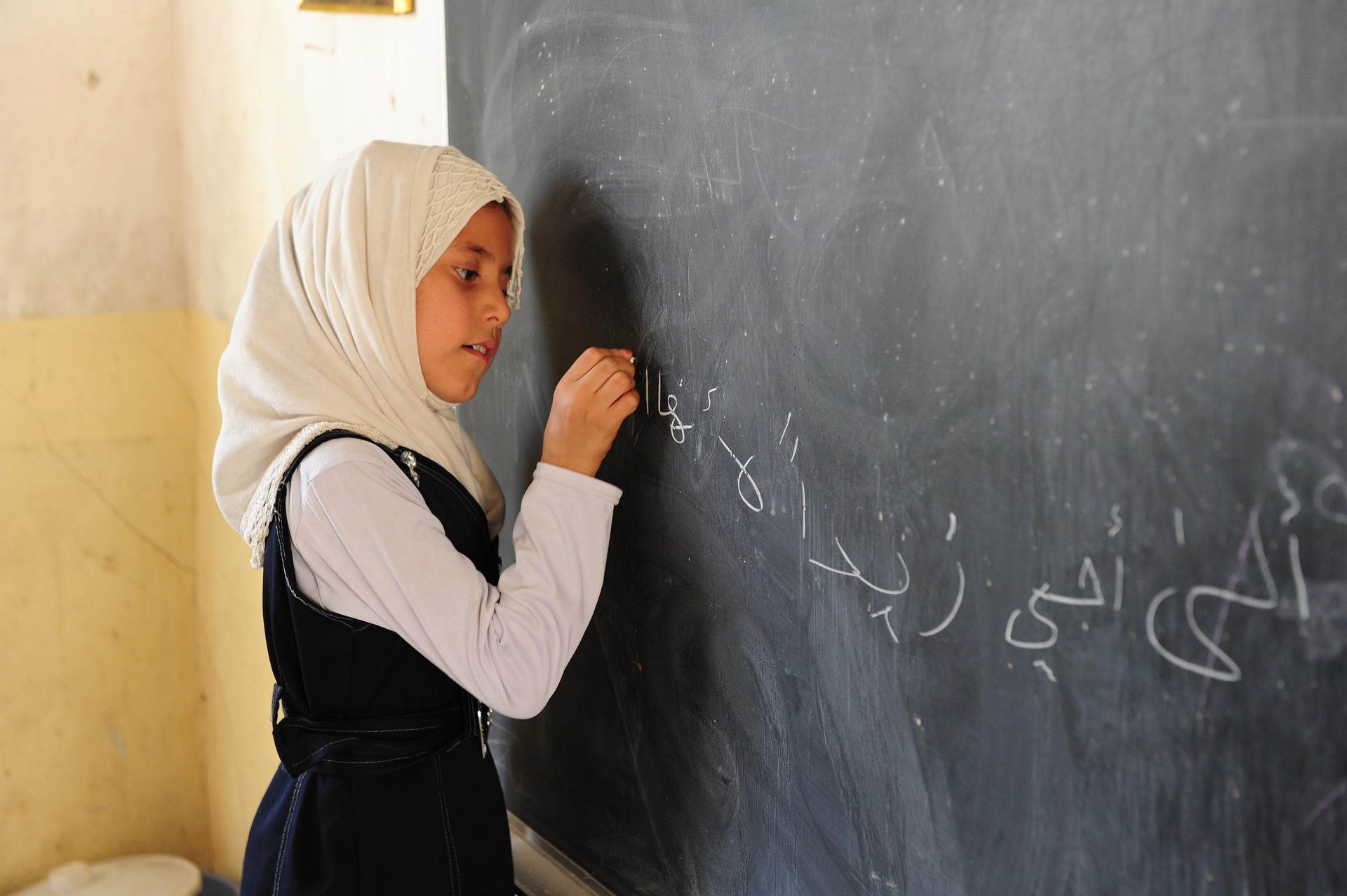 girl pupil writing on blackboard