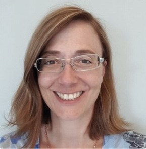 A woman with shoulder-length light brown hair, wearing glasses, smiles at the camera.