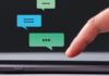 Adventures in WhatsApp A close-up of a finger about to tap on a smartphone screen with floating chat bubbles above it, indicating messaging.