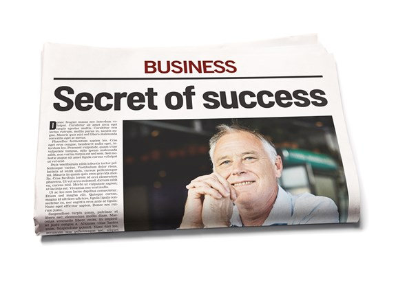 A newspaper showing the headline 'Secret of success' in large bold letters under the section titled 'Business', with a photo of an older man smiling thoughtfully beside it.