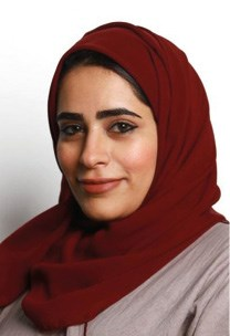Portrait of a person wearing a dark red hijab and a light pink top, smiling slightly.