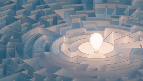 A glowing light bulb at the centre of a circular maze, symbolising the concept of finding solutions or ideas.