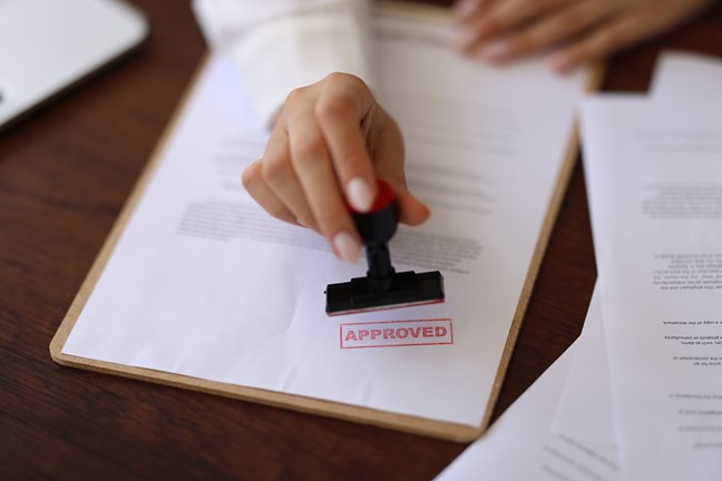 A person's hand stamping a document with 
