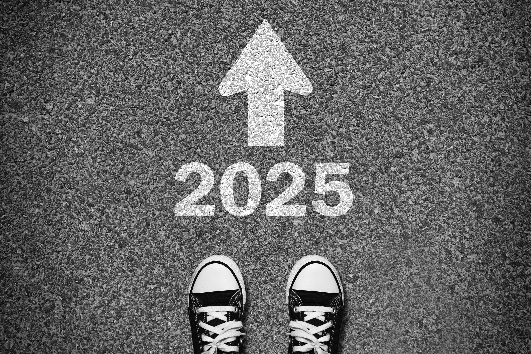 Black and white photo of a pair of sneakers standing on asphalt, with the number 