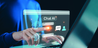 A person in a blue shirt interacts with a holographic display labeled "Chat AI" on a laptop, showcasing digital icons and chat bubbles.