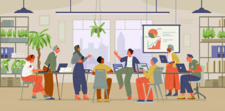 A diverse group of people engaged in a meeting around a table in a modern office. Various plants decorate the office, and a screen displays a chart with pie and line graphs. Laptops and notebooks are placed on the table, while shelves with books and binders line the walls.