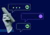 Speaking more, speaking better A hand holding a smartphone with digital speech bubbles on a dark blue background, featuring symbols and text suggesting AI and messaging.