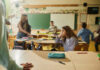 The emotions of inclusion: Building classrooms where everyone belongs The emotions of inclusion: Building classrooms where everyone belongs - A classroom with several children, one of whom is sitting at a desk looking away thoughtfully, while others move around energetically.