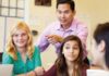 The importance of attitude A teacher stands in a classroom surrounded by a group of diverse students, all seated and looking attentively at the teacher, who is gesturing during a discussion.