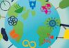 On Reflection Illustration of the Earth surrounded by diverse people and symbols representing sustainability, including a bicycle, plant, book, recycling symbol, and heart with a pulse line, against a blue sky with clouds.