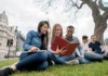 Taking the plunge three students in a park sharing a book